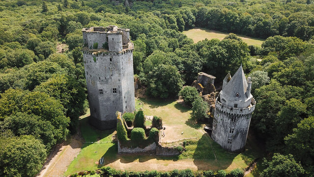 Aerial view of the historic Largoet Castle featuring its two prominent stone towers surrounded by lush green forest in Elven, Bretagne, France.