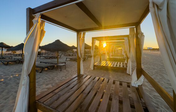 Sunny sunset beach sunbeds umbrella palm trees relax nature outdoors ocean view summer vacation tranquil couple travel tropical paradise luxury resort evening sky scenic shore background