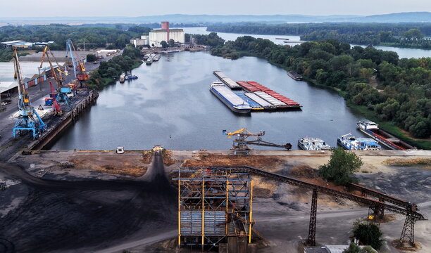 Aerial view of Danube Port with industrial infrastructure, cargo cranes, and barges docked on the river in Pancevo, Serbia.