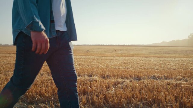 Farmer in casual attire walks across cropped field at sunrise