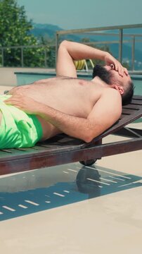 Bearded man sunbathing and relaxing on a lounge chair