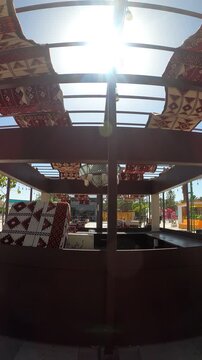 Sunlit Arabic outdoor pergola decorated with traditional red carpets.