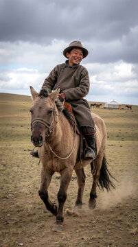A happy Mongolian boy in traditional deel clothing and a hat rides a horse through the vast steppe landscape, expressing joy and freedom under a cloudy sky near a yurt camp.