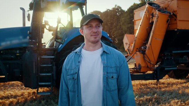 Skilled farmer in cap and denim shirt stands near tractor trailer