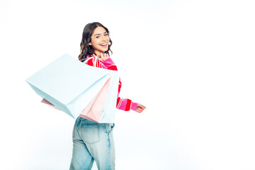 Happy young woman carrying shopping bags over shoulder smiling in casual outfit, lifestyle portrait...