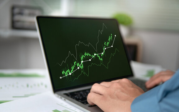 Business investors analyze the green growth graph of the green economy stock market on their laptop screens, focusing on sustainable green investment concepts.