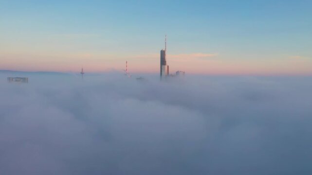 Aerial view of Commerzbank Tower rising above a thick layer of morning fog in Frankfurt am Main, Hessen, Germany.