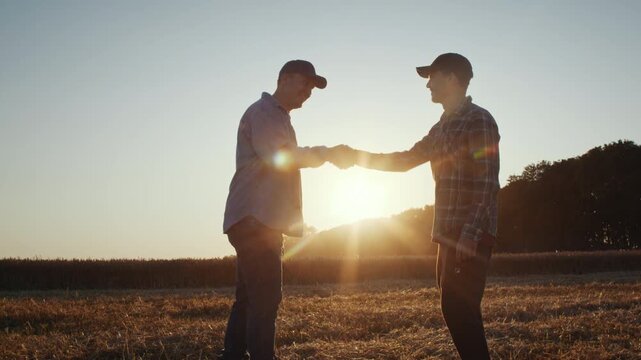 Farmers seal business partnership with handshake in sunset field