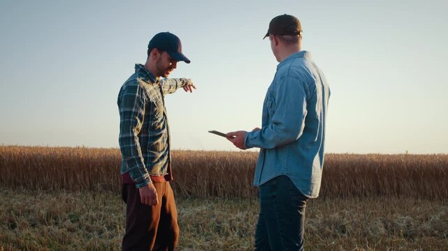 Agronomists discuss crop plans while checking tablet in field