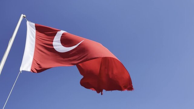 Turkish flag waving proudly in the wind against a clear blue sky, capturing the majestic details of the crescent and star in high-quality 4K footage, perfect for national holidays, patriotic themes, a