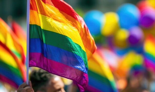 Crowd gathers to celebrate pride with rainbow flags and colorful balloons