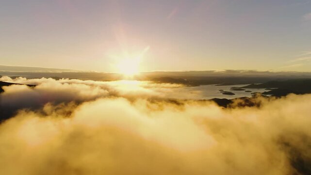 Aerial view of golden sunset light illuminating thick clouds above the Adriatic Sea and islands in Croatia.