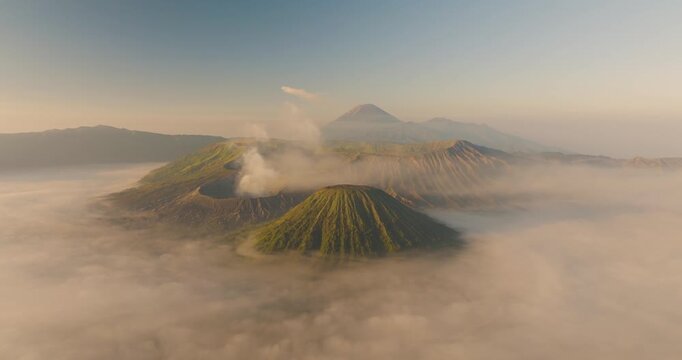 Aerial view of Mount Bromo and Tengger Caldera with volcanic craters rising above a sea of morning mist under soft golden light in Indonesia.