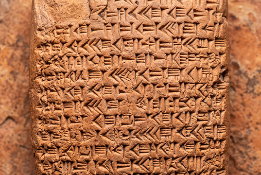 Cuneiform tablet macro with dense wedge clusters on solid warm terracotta background