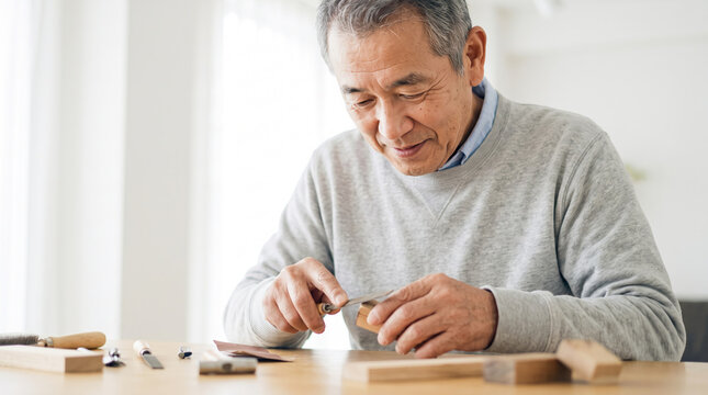 自宅で彫刻刀を使い木工制作を楽しむシニア男性
