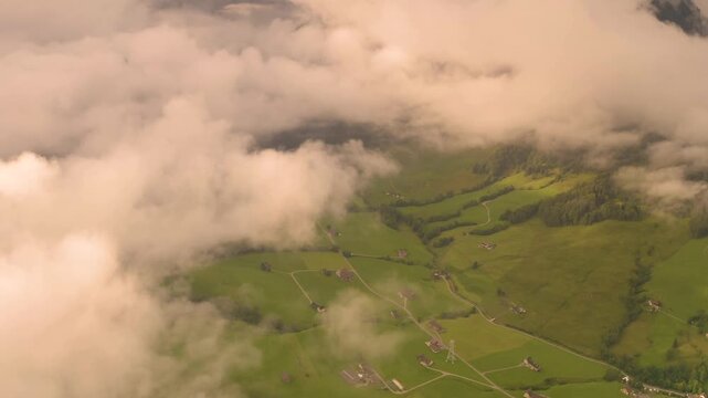 Aerial view of the lush green meadows and rolling hills of the Alpstein mountain range partially obscured by clouds in Appenzell, Appenzell Innerrhoden, Switzerland.