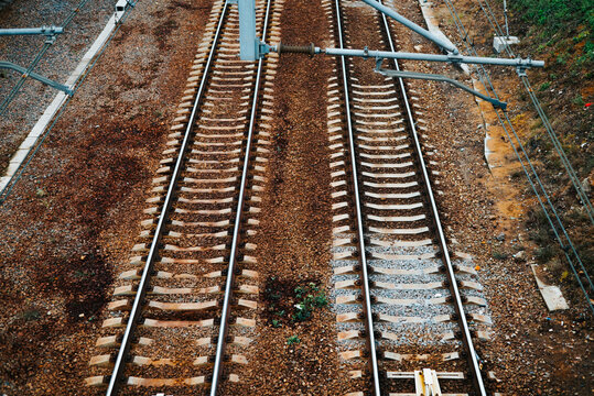 Railway tracks run parallel through a landscape with gravel and vegetation visible on the sides.