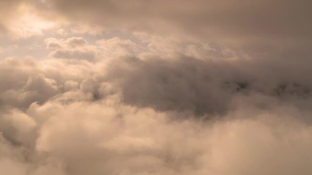 Aerial view of the Alpstein mountain range peaks rising above a thick layer of clouds under a soft golden light in Appenzell, Appenzell Innerrhoden, Switzerland.