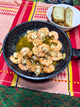 Cooked shrimp scampi in a pan with bread slices
