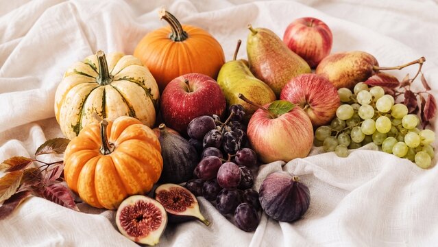 Autumn Harvest Still Life with Fruit and Pumpkins Colorful autumn harvest arrangement with pumpkins, apples, pears, grapes, and figs on soft white fabric, celebrating seasonal abundance and fresh prod