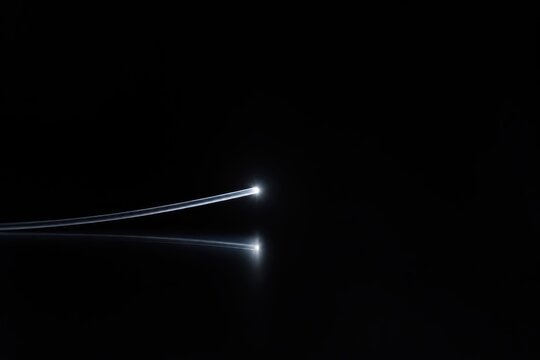 Two aircraft flying at night, leaving bright light trails in the dark sky.