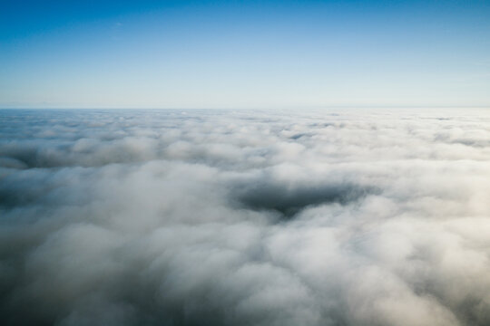 Aerial view of a dense layer of white clouds stretching to the horizon under a clear blue sky in Helsinki, Uusimaa, Finland.