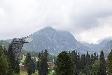 Alpenberg mit dichtem Nadelwald und Skisprungschanze im Nebel © tamaslaza3