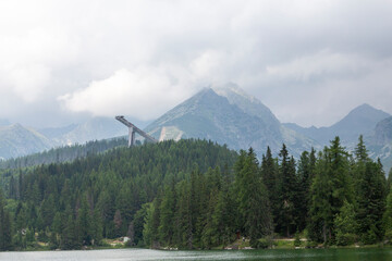 Alpenberg mit dichtem Nadelwald und Skisprungschanze im Nebel © tamaslaza3