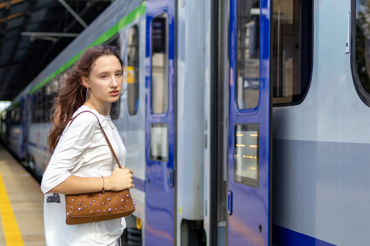 Teenage girl waiting beside the train door before boarding with a bag for her journey. Concept of departure, train travel, independent teenage travel and beginning a new journey.