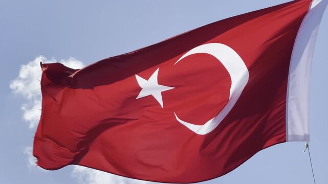 Turkish flag waving proudly in the wind against a clear blue sky, capturing the majestic details of the crescent and star in high-quality 4K footage, perfect for national holidays, patriotic themes, a