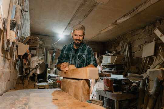 Experienced woodworker planing lumber in a rustic workshop crafting handmade furniture and carpentry projects