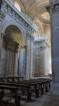 Interior nave of stone church with wooden pews and overhead light