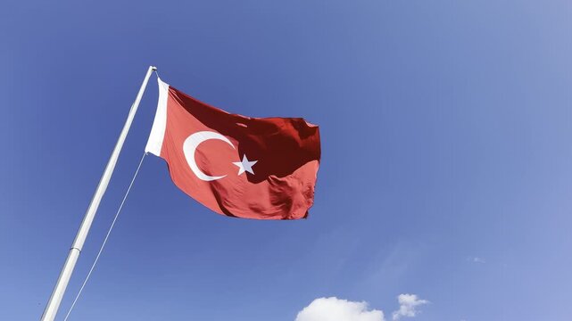 Turkish flag waving proudly in the wind against a clear blue sky, capturing the majestic details of the crescent and star in high-quality 4K footage, perfect for national holidays, patriotic themes, a