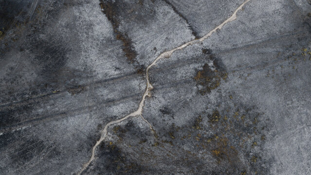 Aerial view of fire-damaged landscape with scorched earth and a winding dirt path, Plevenon, Brittany, France.