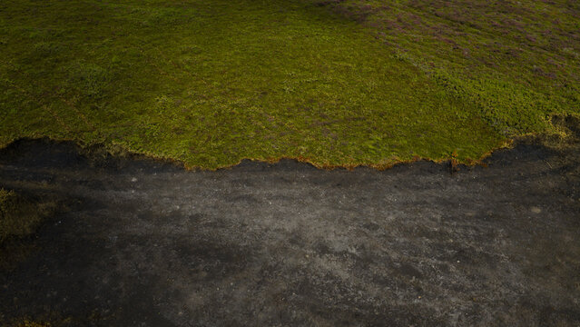 Aerial view of a landscape showing a sharp contrast between vibrant green vegetation and a scorched, burnt area of land in France.