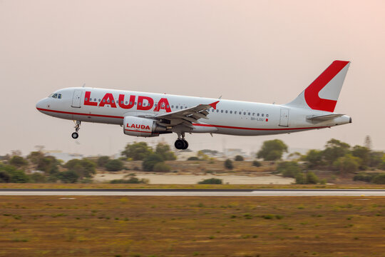 Luqa, Malta - August 29, 2206: Lauda Europe Airbus A320-214 (REG: 9H-LOU) landing in the early morning with an unusually orange sky due to Saharan desert sand present in the atmosphere.