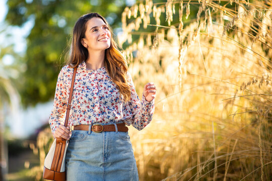 Happy woman walking through sunny park with natural smile