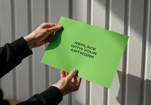 Paper mockup held by hands against a vertical slatted wall, realistic stationery presentation with natural light, interior office setting, Template