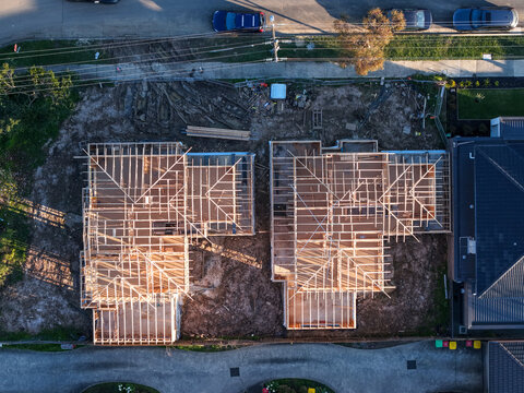 Aerial view of two residential houses under construction with exposed wooden roof frames in a suburban neighborhood in Boronia, Victoria, Australia.