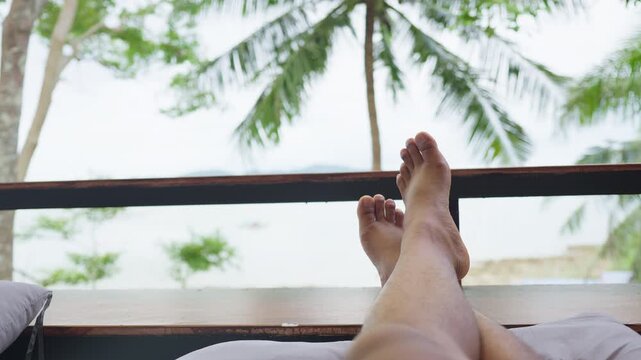First-person view of someone relaxing with their feet propped up on a balcony, enjoying the serene ocean scenery during a tropical island getaway.