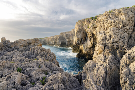 Dramatic sunny rocky cliffs formation with raging sea and extreme terrain
