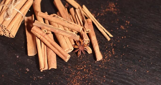 Cinnamon sticks and star anise on a dark surface with coffee beans, aromatic spices and coffee beans, spice theme, coffee theme, culinary theme
