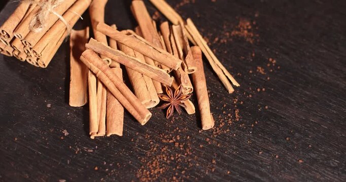 Cinnamon sticks and star anise on a dark surface with coffee beans, aromatic spices and coffee beans, spice theme, coffee theme, culinary theme
