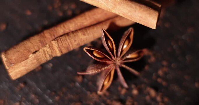 Cinnamon sticks and star anise on a dark surface with coffee beans, aromatic spices and coffee beans, spice theme, coffee theme, culinary theme
