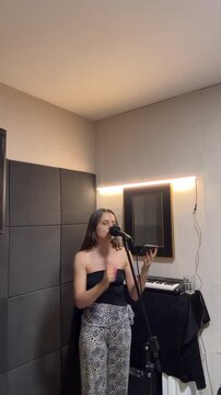 Mulher canta com microfone em est&uacute;dio 
