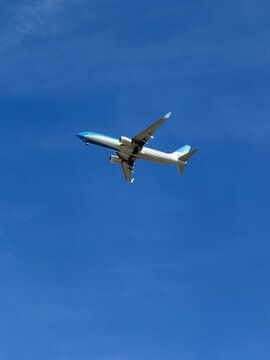 Modern commercial passenger airplane flying through a clear vibrant blue sky, low-angle view with ample copy space for travel stock.