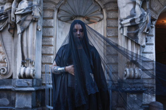 Mourning woman in black lace veil with silver bracelet, widow image, grief and sorrow concept.