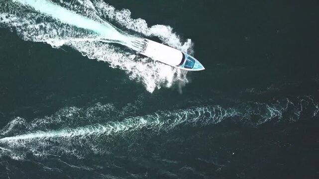 Aerial view of high speed motorboat traveling fast across deep blue ocean water.