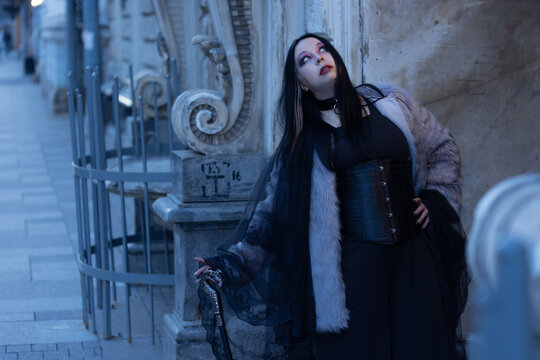 Dreaming woman in gothic outfit leaning on old wall and looking up, inspiration and hope.
