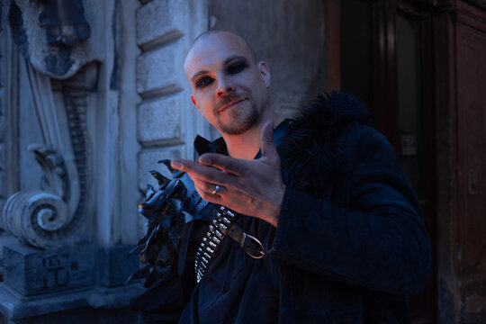 Man in gothic coat showing open palm to camera, presentation and offer gesture, copy space.